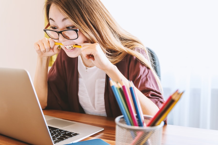 A student studying at a desk with a laptop and coloured pencils