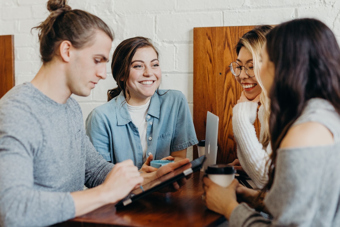 Four friends talking and laughing together around a cafe table